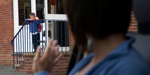 Boy (5-7) standing on school steps waving goodbye to mother in car