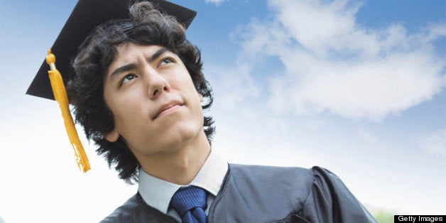 Contemplative young Asian man wearing graduation cap and gown