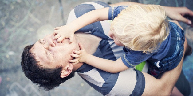 Little boy being silly grabbing his daddys face.