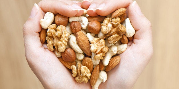 Various nuts in woman hands forming heart shape