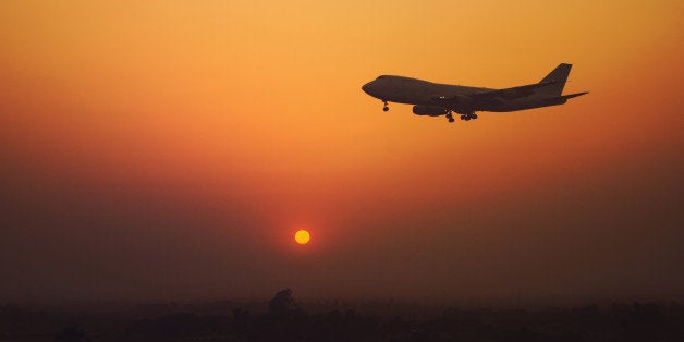 Plane flying in the evening sky while the sun is setting behind.