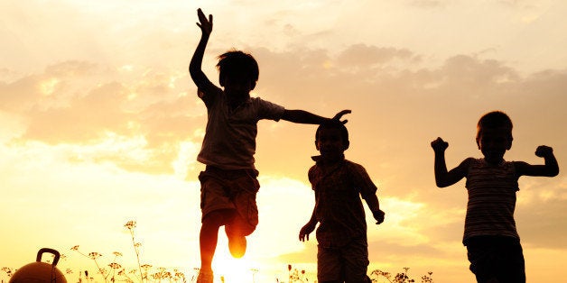 Silhouette, group of happy children playing on meadow, sunset, summertime