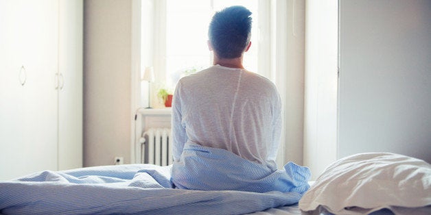 Young man sitting on bed