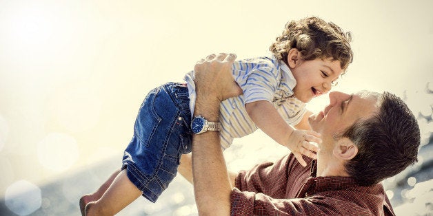 Father holding two years old son in the beach.