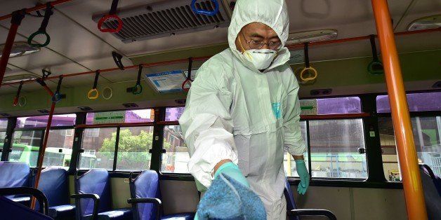 A South Korean health worker wearing protective gear sanitizes a chair in a public bus at a transport company in Seoul on June 15, 2015. South Korea reported on June 15, two more deaths and five new cases in the growing outbreak of MERS which has placed more than 5,200 people under quarantine and sparked widespread alarm. AFP PHOTO / JUNG YEON-JE (Photo credit should read JUNG YEON-JE/AFP/Getty Images)
