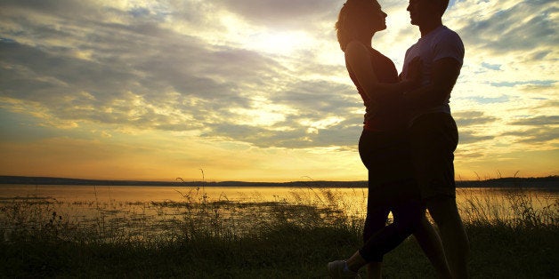 Silhouettes of a young couple lovers at sunset in rays of setting sun