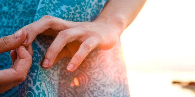 Woman standing on beach and pressing her finger during sunset.