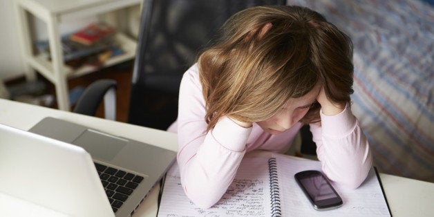 Girl Using Mobile Phone Instead Of Studying In Bedroom with her head in her hands