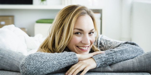 Germany, Bavaria, Munich, Portrait of young woman relaxing on couch, smiling