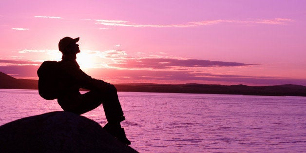 'Silhouette of the man resting on the rock, sunset, lake on the background. Toned.concepts: Freedom, Travel, ContemplatingSee also'