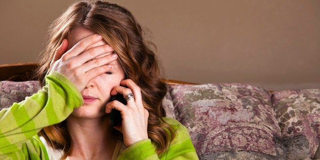 Attractive young woman receives bad news via mobile phone.