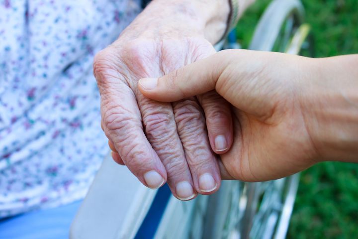 caregiver holding senior's hand ...