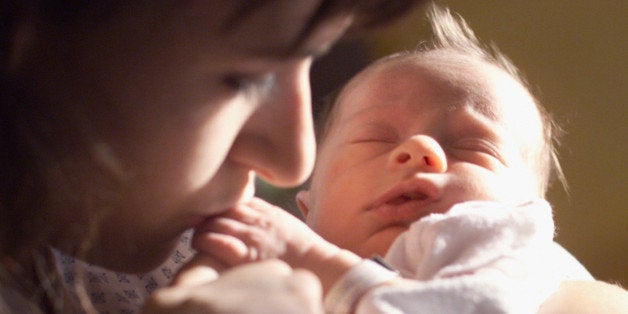 a caucasian brunette female mother holds her newborn baby