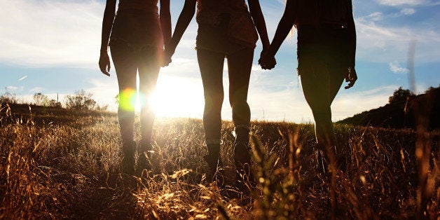 Silhouette of three girls walking into sunset