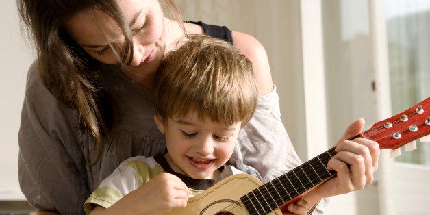 Young Mother Showing her Son how to Play Guitar