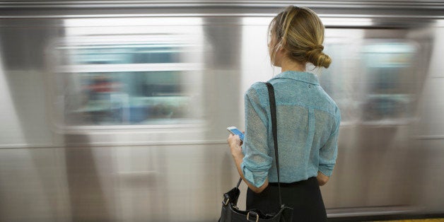 Caucasian woman standing near passing subway in train station