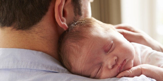 Father At Home Holding Sleeping Newborn Baby Daughter