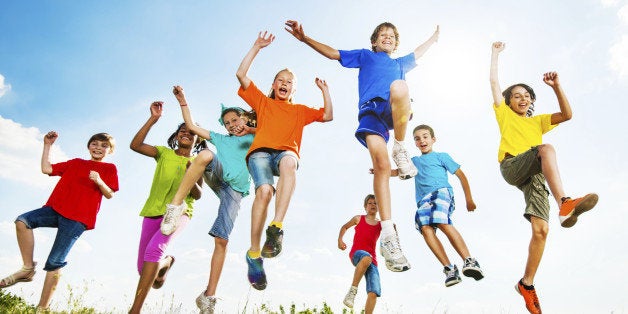 Happy children jumping with raised arms and enjoying in a beautiful nature.