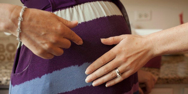 Emily Jordan, right, examines the pregnant belly of her mother Cindy Reutzel on Sunday, Aug. 19, 2012 in Naperville, Ill. After Jordan underwent a radical hysterectomy, she and her husband took up an offer from Reutzel to act as their surrogate. (AP Photo/Sitthixay Ditthavong)