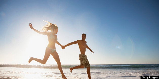 Couple holding hands and running on beach