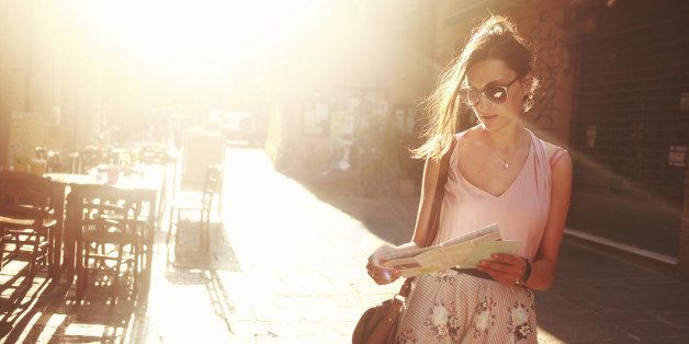 young brunette sightseeing on the street, looking at the map, lit by the magic hour sunlight.