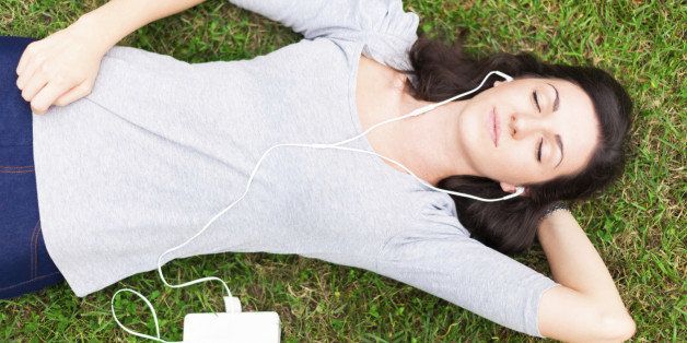 Woman relaxing on the grass while listening music