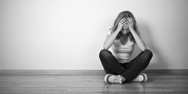 girl sits in a depression on the floor near the wall monochrome