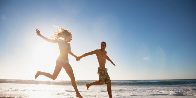 Couple holding hands and running on beach