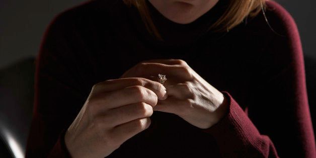Woman adjusting wedding ring, mid section (focus on hands)