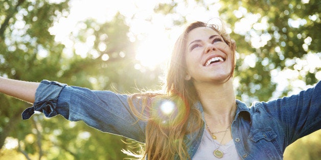 A shot of a young woman standing outdoors with her arms outstretched