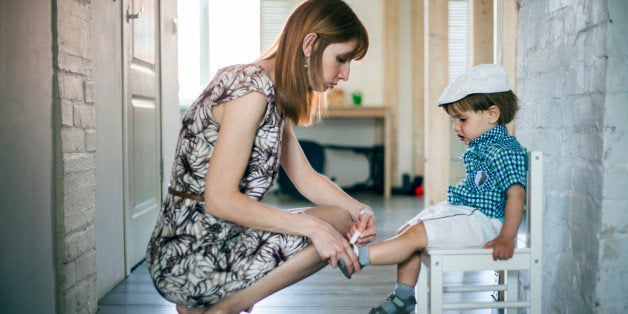 Mother putting shoes and socks on baby son