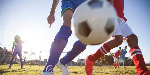 Close up action of boys soccer teams, aged 12-14, playing a football match