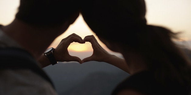 Cropped view of the silhouette of two hands making a heart-shape