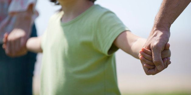Boy holding hands with parents, cropped