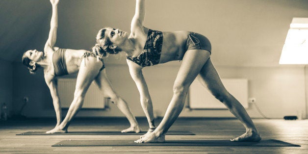 Two young women are exercising bikram yoga