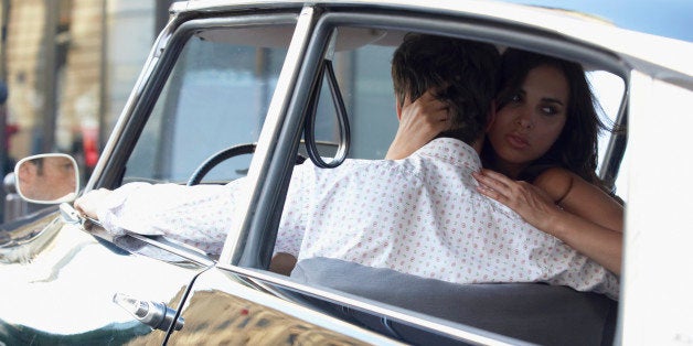 Couple in car, woman embracing man and looking over shoulder