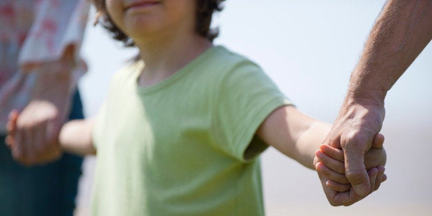 Boy holding hands with parents, cropped