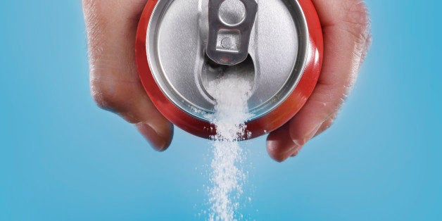 hand holding soda can pouring a crazy amount of sugar in metaphor of sugar content of a refresh drink isolated on blue background in healthy nutrition, diet and sweet addiction concept