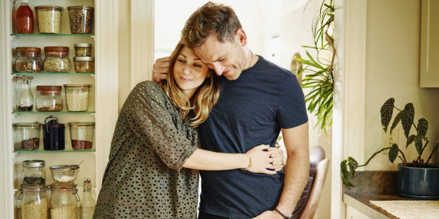 Smiling couple embracing in doorway of kitchen