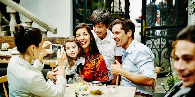 Smiling family posing for photo at table during family dinner party in restaurant