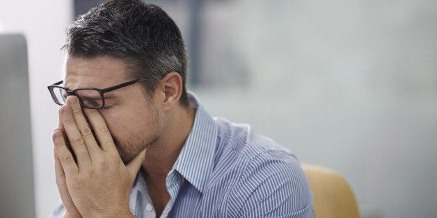 A cropped shot of a stressed businessman sitting at his desk