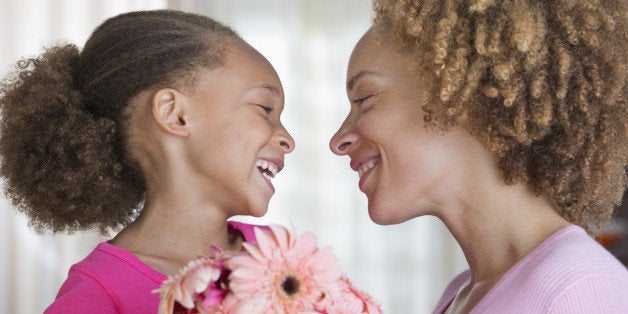 Black mother and daughter holding bouquet of flowers