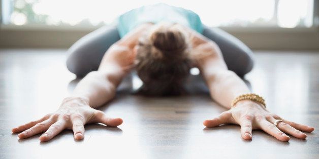 Woman practicing yoga in childs pose stretching arms