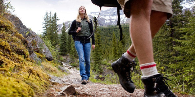 A happy woman on a mountain trail with mountains in the background
