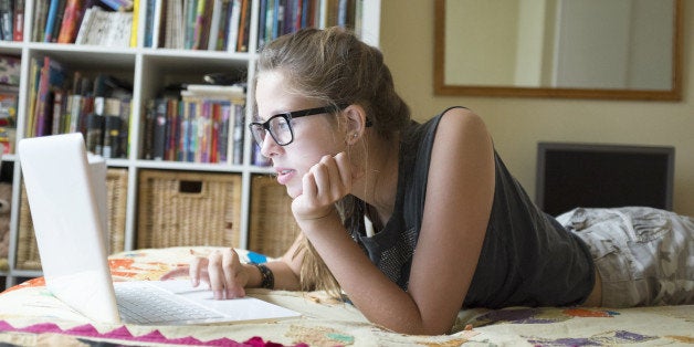 Teenage girl lying on front using laptop