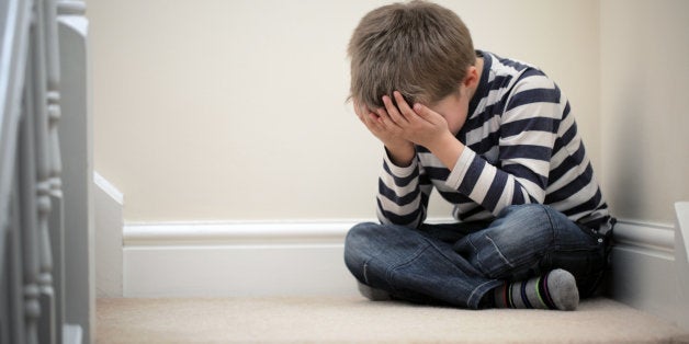 Upset problem child with head in hands sitting on staircase concept for childhood bullying, depression stress or frustration