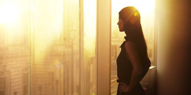 Business woman looking over the city at sunrise.