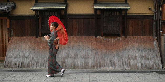 Japan, Kyoto, Gion, woman in kimono with red oilpaper umbrella, walking in street