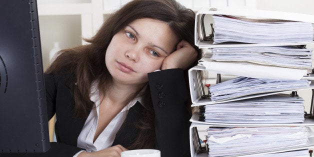 Stressed Businesswoman Working In Office With Stack Of Folders