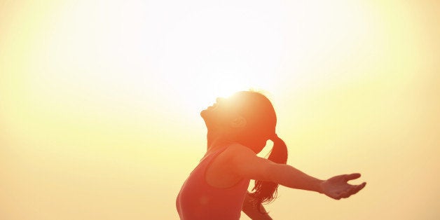 cheering woman open arms at sunrise beach